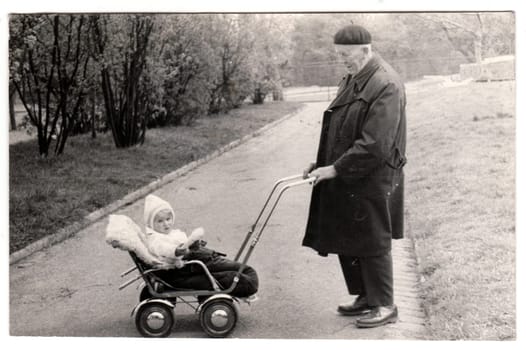 THE CZECHOSLOVAK SOCIALIST REPUBLIC - CIRCA 1950s: Vintage photo shows grandfather with a small baby in the pram - carriage. Retro black and white photography. Circa 1950.