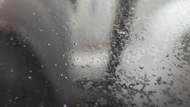 Water drops on black plastic. Surface with wet background. Abstract texture and pattern full of water. Raindrops of rain for overlaying on window with partial focus. Concept of autumn weather