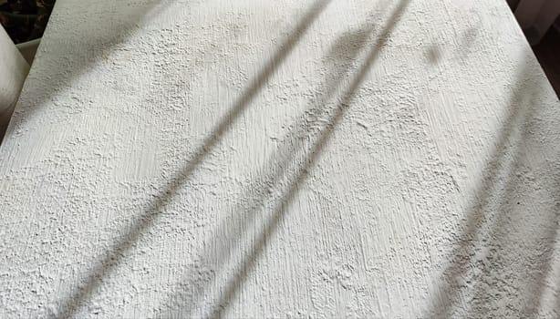 Abstract pattern with stripes and lines of shadow and light from sun on textured white whitewash, plaster, paint. Background and texture