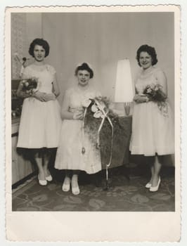 THE CZECHOSLOVAK SOCIALIST REPUBLIC - CIRCA 1960s: Vintage photo shows a bride with bridesmaids. Bride wears a soft veil and holds calla flowers - bouquet. Retro black and white photography. Circa 1960.