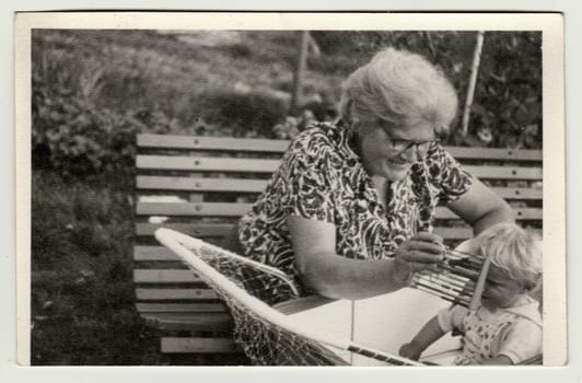 THE CZECHOSLOVAK SOCIALIST REPUBLIC - CIRCA 1950s: Vintage photo shows grandmother with a small baby in the pram - carriage. Grandmother holds abacus. Retro black and white photography. Circa 1950.