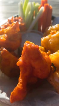 Vegan cauliflower Buffalo wings with ranch sauce and fresh celery and carrot sticks. Bar food in Baja California, Mexico. Backlit in the sun.