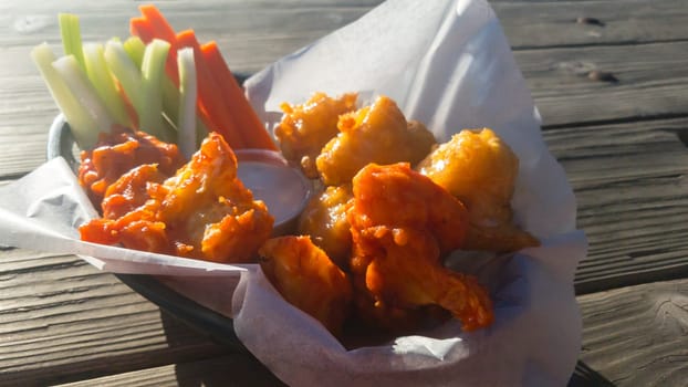 Vegan cauliflower Buffalo wings with ranch sauce and fresh celery and carrot sticks. Bar food in Baja California, Mexico. Backlit in the sun.