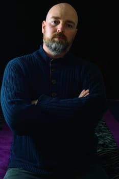 Well dressed caucasian male, late thirties, in dark clothes on dark background. Studio shot with side lighting, low key portrait