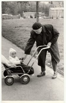 THE CZECHOSLOVAK SOCIALIST REPUBLIC - CIRCA 1950s: Vintage photo shows grandfather with a small baby in the pram - carriage. Retro black and white photography. Circa 1980.