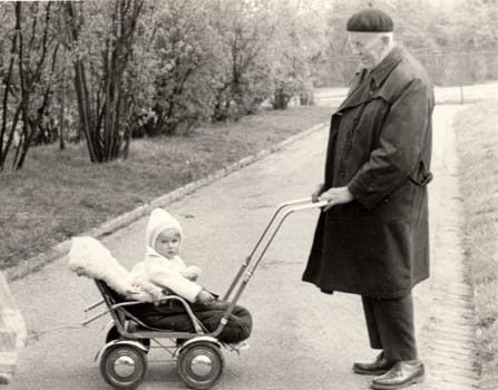 THE CZECHOSLOVAK SOCIALIST REPUBLIC - CIRCA 1950s: Vintage photo shows grandfather with a small baby in the pram - carriage. Retro black and white photography. Circa 1950.