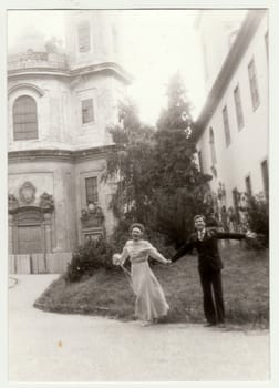 THE CZECHOSLOVAK SOCIALIST REPUBLIC - CIRCA 1980s: Vintage photo shows young newlyweds - bridal couple in front of church. Retro black and white photography. Circa 1980.