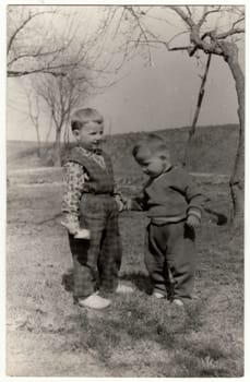 THE CZECHOSLOVAK SOCIALIST REPUBLIC - CIRCA 1960s: Vintage photo shows two small boys play outdoors. Funny and cute photo. Retro black and white photography. Circa 1960.