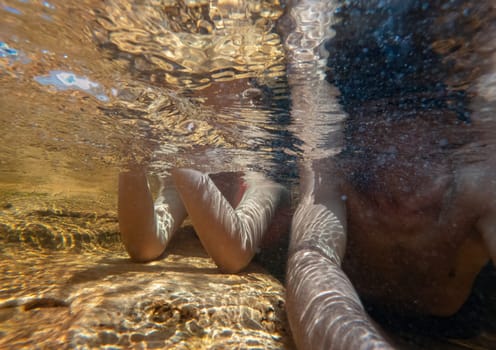 A male and female body under the water, unrecognizable, lying in a shallow river area, enjoying the moment, the anonymity, with space for text and lots of water.
