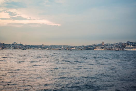 Istanbul at sunset, Turkey. Tourist boat sails on Golden Horn in summer. Beautiful sunny view of Istanbul waterfront with old mosque. Concept of travel, tourism and vacation in Istanbul and Turkey. Turkiye.