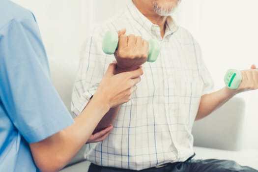 Contented senior patient doing physical therapy with the help of his caregiver. Senior physical therapy, physiotherapy treatment, nursing home for the elderly