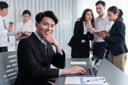 Portrait of focus young successful confident male manager, executive wearing business wear in harmony office arm crossed with blurred meeting background of colleagues, office worker.