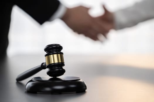 Focus gavel symbolize justice on blur background of lawyer colleagues handshake after successful legal deal for lawsuit to advocate resolves dispute in court ensuring trustworthy partner. Equilibrium