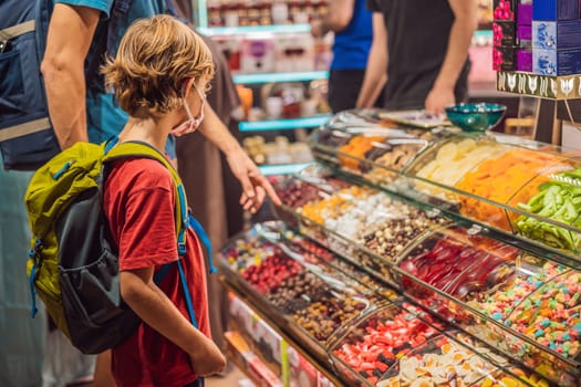 The boy looks at the counter with Turkish sweets. Traditional oriental sweet pastry cookies, nuts, dried fruits, pastilles, marmalade, Turkish desert with sugar, honey and pistachio, in display at a street food market.