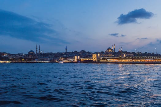 Istanbul at sunset, Turkey. Tourist boat sails on Golden Horn in summer. Beautiful sunny view of Istanbul waterfront with old mosque. Concept of travel, tourism and vacation in Istanbul and Turkey. Turkiye.