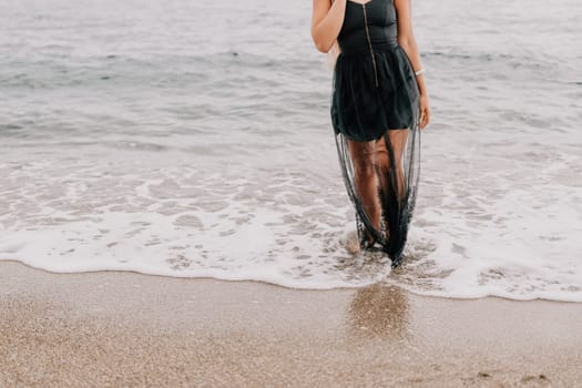 Woman travel sea. Young Happy woman in a long red dress posing on a beach near the sea on background of volcanic rocks, like in Iceland, sharing travel adventure journey