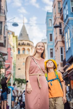 Portrait of beautiful mother and son tourists with view of Galata tower in Beyoglu, Istanbul, Turkey. Turkiye. Traveling with kids concept.