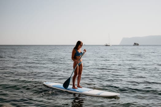 Close up shot of happy young caucasian woman looking at camera and smiling. Cute woman portrait in bikini posing on a volcanic rock high above the sea