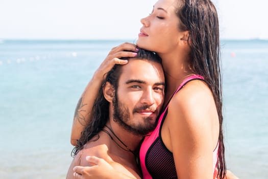 Close up shot of beautiful young caucasian woman with black hair and freckles looking at camera and smiling. Cute woman portrait in a pink bikini posing on a volcanic rock high above the sea