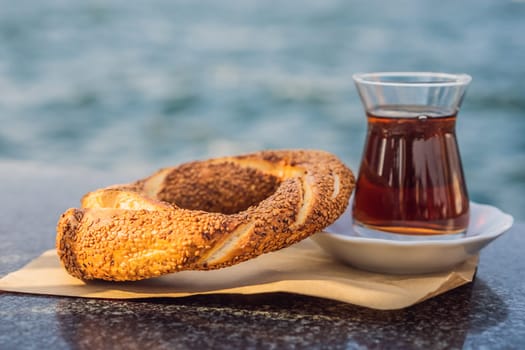 A glass of Turkish tea and bagel Simit against golden horn bay in Istanbul, Turkey. Turkiye.