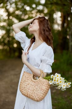 portrait of a beautiful red-haired woman with a wicker basket in her hands, holding her hair with her hand, walks in the park. High quality photo