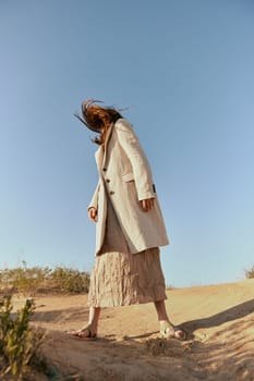 stylish woman in fashion style posing on the sand covering her face with her hair in motion. High quality photo