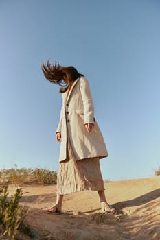 stylish woman in fashion style posing on the sand covering her face with her hair in motion. High quality photo