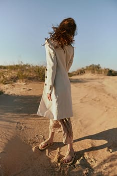 a woman in stylish, summer clothes stands in poses posing with her face covered by her hair. High quality photo