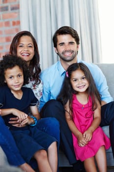 Family comes first. Portrait image of an adorable family sitting on the sofa in their home