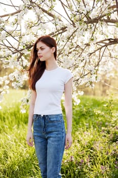 Beautiful young woman near blooming tree on spring day. High quality photo