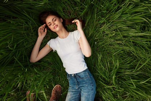 a woman lies in the tall grass with her eyes closed. High quality photo