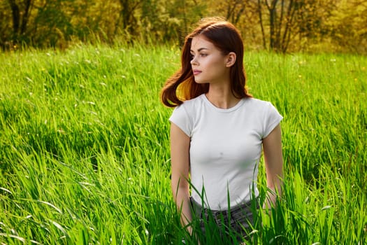 portrait of a woman sitting in tall grass and lit by the sun from the back. High quality photo