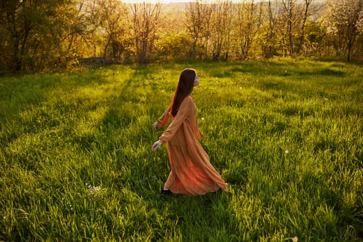 a joyful woman runs through a green field with her hands behind her back, enjoying a warm summer day and nature during the sunset. Horizontal photography in nature. High quality photo