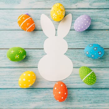 Easter Day Concept. Top view holiday banner background web design white colorful easter eggs and paper bunny rabbit on blue wood background with copy space, celebration greeting, overhead, template