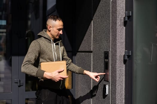 Happy man ringing intercom with camera in entryway