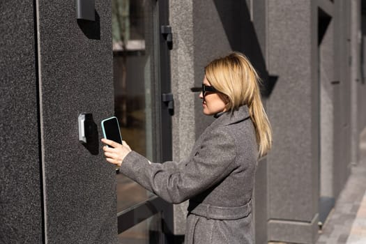 Smart home concept - close up of woman use mobile phone to open electronic lock.