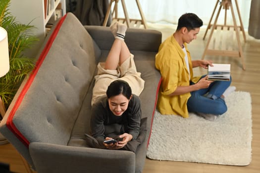 Overhead view of young couple sitting in living room, spending tome together at home. Love, people and lifestyle concept.