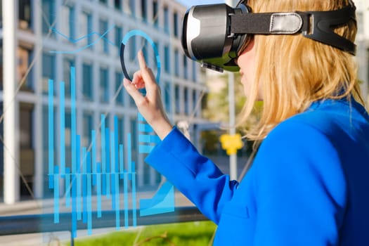 Young woman using virtual reality goggles to analyze data and graphics in colorful neon lights. Futuristic future concept in business.