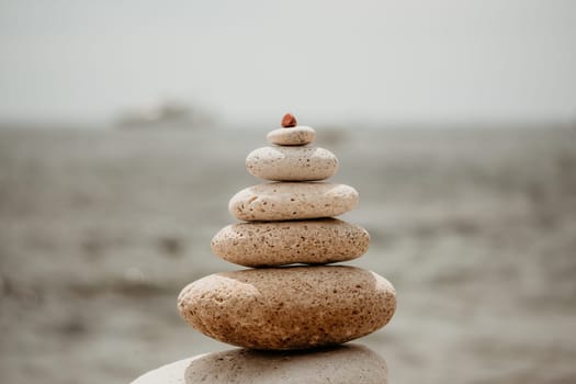 Pyramid stones on the seashore with warm sunset on the sea background. Happy holidays. Pebble beach, calm sea, travel destination. Concept of happy vacation on the sea, meditation, spa, calmness.