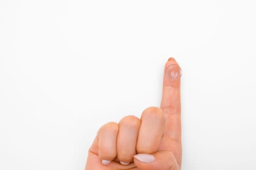 Close up finger with contact lens on the white background. Eye treatment concept