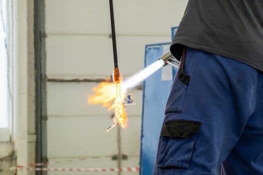 A man uses a gas burner to melt glass. A craftsman makes a glass in a leaf shaped.
