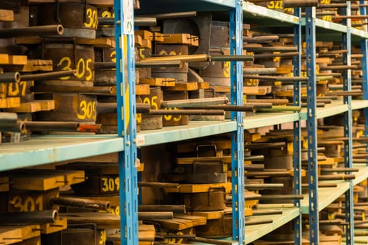 Metal molds for the production of various shapes of glass products lie on the shelves in the factory or glass manufacture.