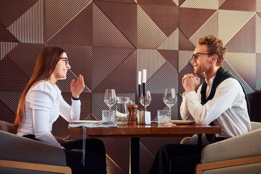 Young boyfriend with adult woman. Indoors of new modern luxury restaurant.