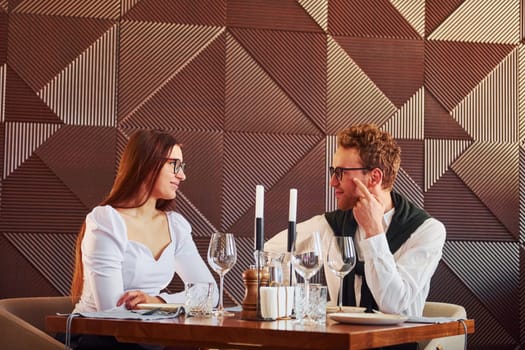 Young boyfriend with adult woman. Indoors of new modern luxury restaurant.