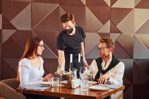 Young boyfriend with adult woman. Indoors of new modern luxury restaurant.