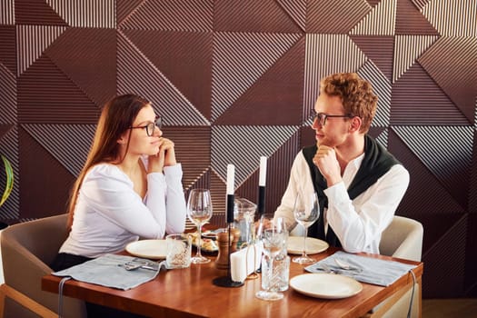 Young boyfriend with adult woman. Indoors of new modern luxury restaurant.