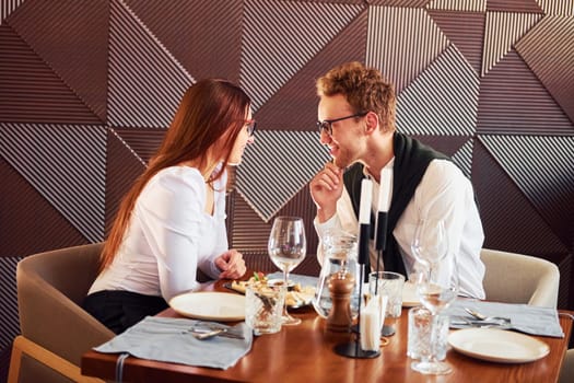 Young boyfriend with adult woman. Indoors of new modern luxury restaurant.