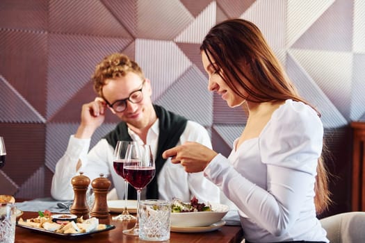 Man in glasses is with woman. Indoors of new modern luxury restaurant.