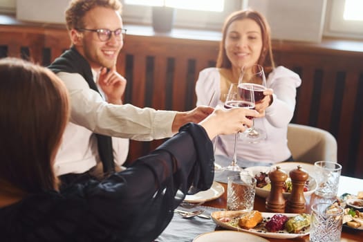 Cheering with glasses of wine. Indoors of new modern luxury restaurant.