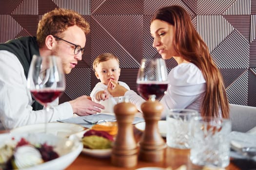 Young guy, woman and little boy. Indoors of new modern luxury restaurant.